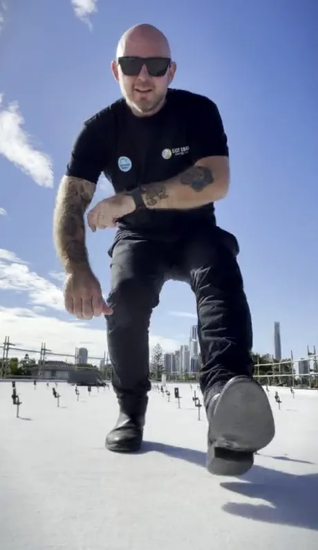 Chris Kennedy kneeling on a roof in an East Coast Energy shirt