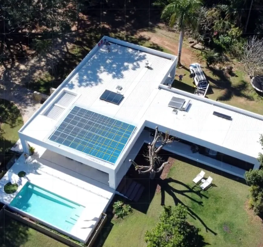 Aerial view of a white modern home with a pool and a solar array on its flat roof