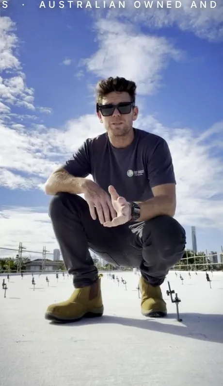 Ryan Quinlivan crouching on a roof in an East Coast Energy shirt